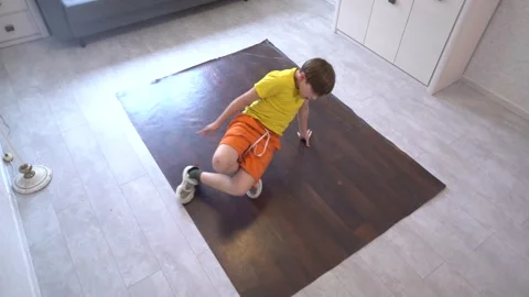 Child practices breakdancing moves at home on wooden floor during afternoon Video stock 311014481