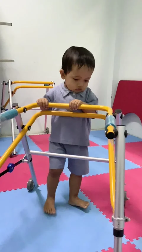 Child practicing walking with a pediatric mobility walker Stock Footage 341498561