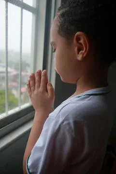 Child praying in window Stock Photos