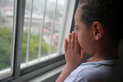 Child praying in window Stock Photos