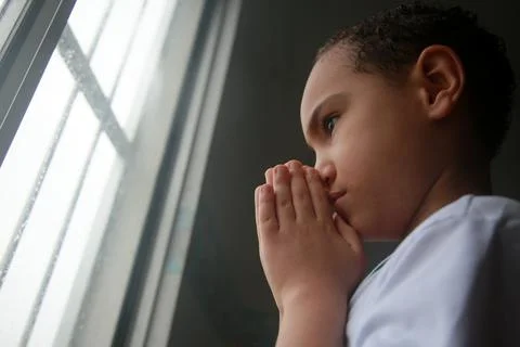 Child praying in window Stock Photos