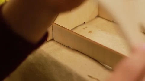 A child prepares to install a side wall from plywood craft in shape of birdhouse Stockbeeldmateriaal 228096011