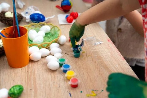 Child preparing to paint Easter eggs with vibrant paints at the table 库存照片