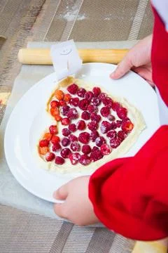 The child is preparing a pizza with berries. raspberry and strawberry. hands in Stock Photos