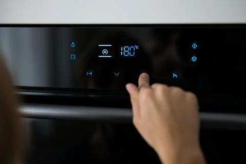 A child presses a button on the touch screen of a modern electric oven Foto stock