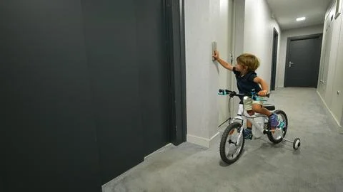 Child pressing elevator button entering with bicycle Foto stock