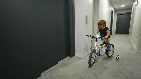 Child pressing elevator button entering with bicycle Foto stock