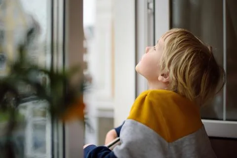 A child of primary school age is at risk of falling from a window Stock Photos