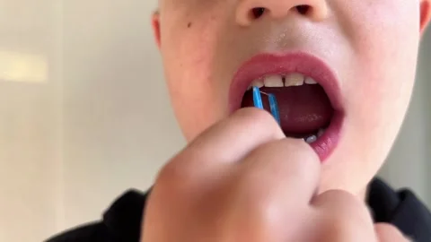 Child with primary teeth cleans between teeth with a floss pick, enamel changes Stock Footage 346153471