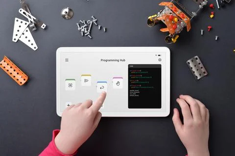 Child programing robot on tablet amidst small parts on work table Stock Photos