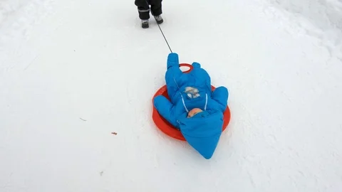 Child pulls a sled with a baby on it in winter Park Stock Footage 101387509
