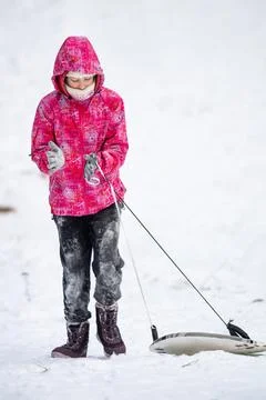 Child pulls a sled on a snowy winter hill. Stock Photos