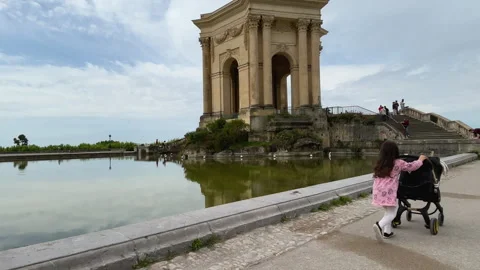 Child Pushing Stroller by Historic Monument and Reflecting Pool in Montpellier Stock Footage 337722575
