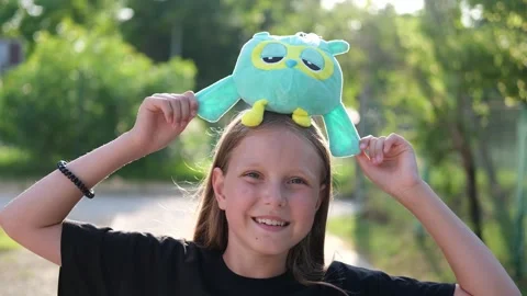 The child put a soft toy on her head and grimaces. Stock Footage 248607677