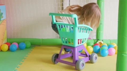 Child puts balls in basket, cleans, proper upbringing, housekeeping girl, smart Stock Footage 171874953