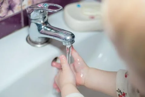 Child puts hands under stream of water from tap. Saving water. cleaning hand to Stock Photos
