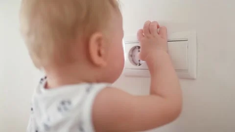 The child puts his fingers in the socket, but there is a blocker for sockets Stock Footage 130452260