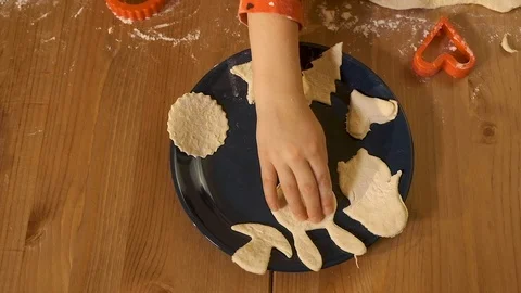 The child puts pieces of dough of different shapes on a plate for baking cookies Stock Footage 120357459