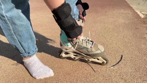 A child puts roller skates on his feet , legs in roller skates close-up, active Stock Footage 241798533