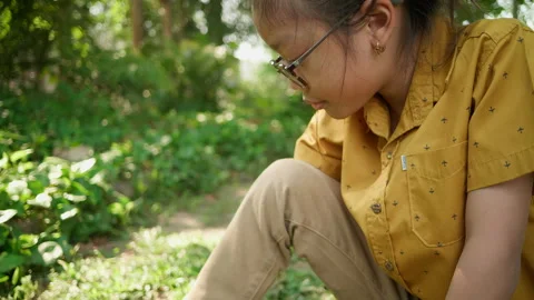 Child putting on shoes while kneeling on the grass in nature Stock Footage 306727488