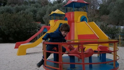 The child quickly spin on the carousel in the playground in the spring Stock Footage 74732580