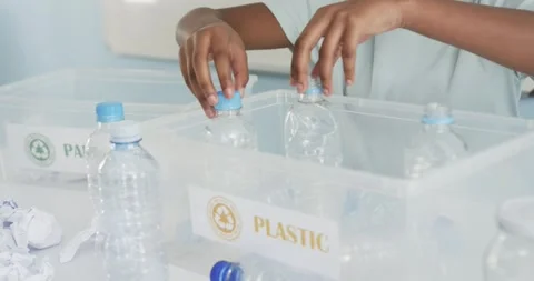 Child is reaching and is sorting bottles on table, is placing into PLASTIC bin Stock Footage 335131223