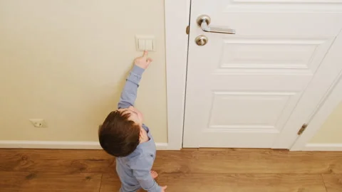 Child reaching to turn on electric light switch on wall. Little boy tapping Vidéo 342278387