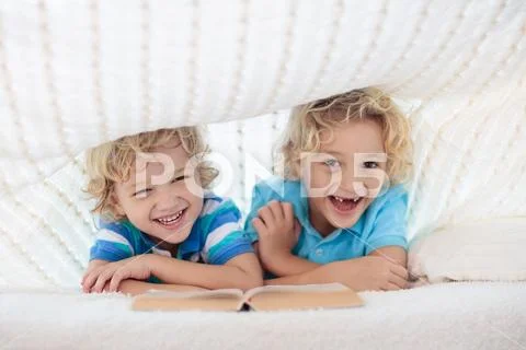 Child reading book in bed. Kids read books. Stock Photos
