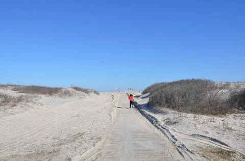 Child in red coat running on sand path at beach Stock Photos