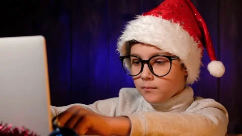 Child in a red hat writes letter to Santa Claus on laptop on Christmas Eve. Stock Footage 166899487