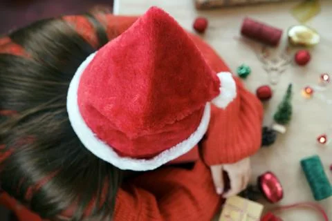 A child in red pullover and Santa Claus hat slipping on the table Stock Photos
