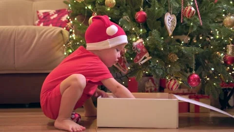 Child red santa hat sit floor indoors playing christmas baubles sweet moments Stock Footage 220791531