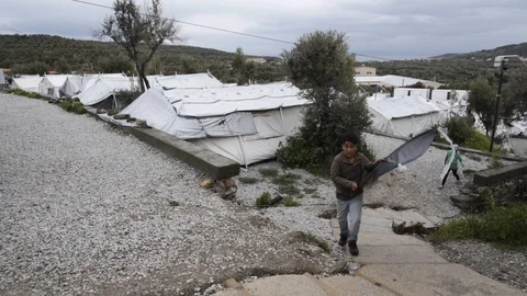 Child refugee with a kite walking by in makefshit camp in slow motion 스톡 동영상 116389298