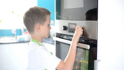 Child regulates temperature of electric kitchen oven Stock Footage 76531472