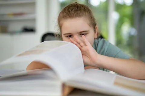 Child relaxing while reading a book at home. Happy kid exploring literature in Stock Photos