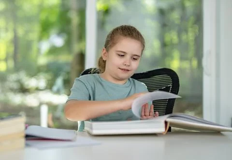 Child relaxing while reading a book at home. Happy kid exploring literature in Stock Photos