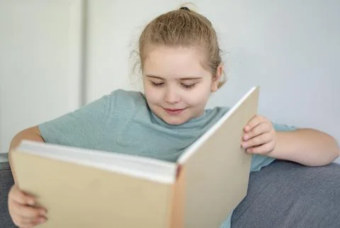 Child relaxing while reading a book at home. Happy kid read book in a home Stock Photos