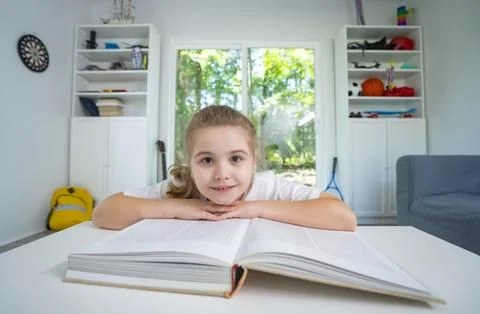 Child relaxing while reading a book at home. Happy kid exploring literature in Stock Photos