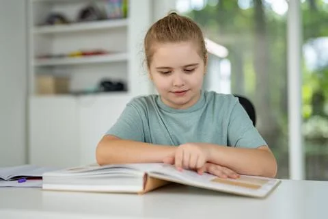 Child relaxing while reading a book at home. Happy kid exploring literature in Stock Photos