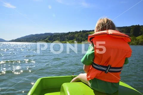 Child rides on boat with life jacket Stock Photos