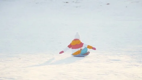 Child rides a sledding down a winter hill  Girl spinning on snow disk Stock Footage 71330522