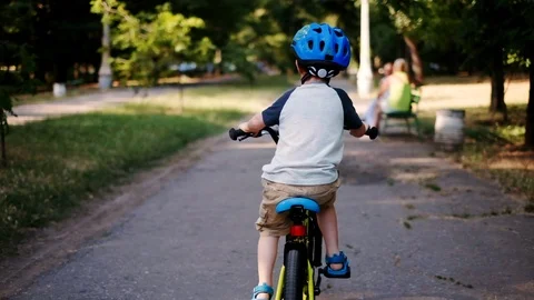Child riding bicycle in park. Kid in helmet learning to ride at summer. Stock Footage