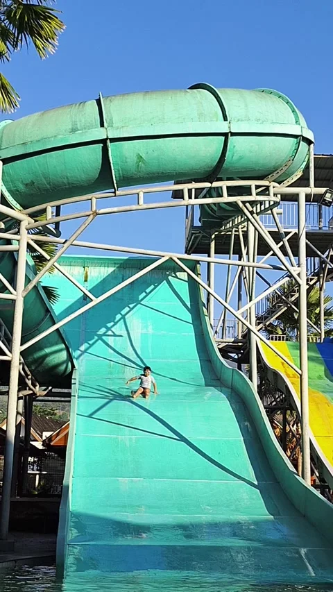 Child riding a giant water slide at an outdoor water park Vídeos de archivo 340441253