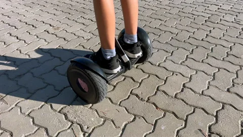 Child riding hoverboard on pavement, close up legs and shoes in slow motion Video stock 331163964