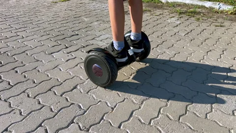 Child riding hoverboard on pavement at sunset, close up legs in slow motion 4K30 Stock-Footage 331196188