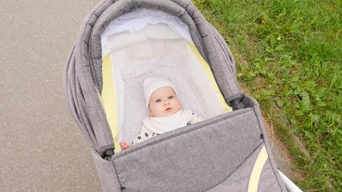 The child is riding in the stroller and is looking at the camera Stock Footage 95744089