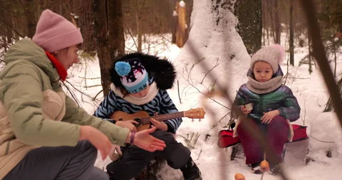 Child roasting marshmallows by snow campfire winter forest scene cozy clothing Stock Footage 303623989