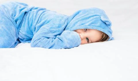 A child in the robe is lying on the bed. Stock Photos
