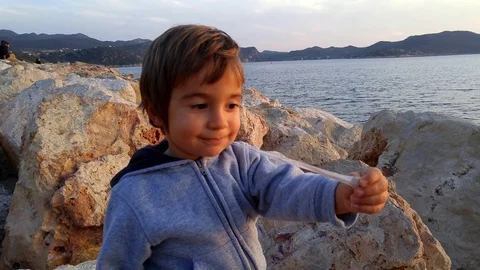 Child on rocks and his chewing-gum Stock Footage 71024090