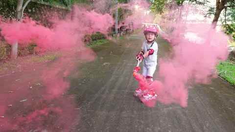 Child on roller skates circles stick with smoke bomb, red puffs fly towards Stock Footage 303625097